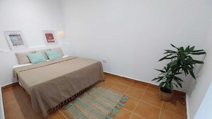 A bedroom with a bed, a rug, a potted plant, and two framed pictures on the wall. - Mar, Montaña y Relax con Vistas al mar (CT)