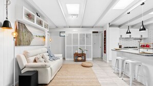 Une cuisine moderne avec des meubles blancs, un îlot central et des tabourets de bar.