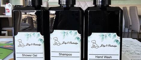 Three black bottles labeled 'Shower Gel,' 'Shampoo,' and 'Hand Wash' with a 'Dog & Partridge' logo.