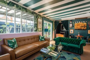 A living room with a brown leather sofa, a green velvet sofa, and a glass coffee table.