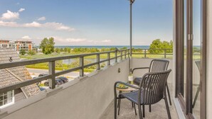 A balcony with two chairs, a table, and a view of a river and buildings. - Bunk 21 Heiligenhafen Studio-Apartment (Heiligenhafen)