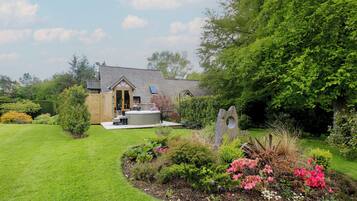 A house with a garden, a hot tub, and a wooden deck.