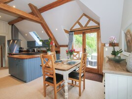Una cocina con techo de madera, una zona de comedor con mesa y sillas, y vistas al exterior.