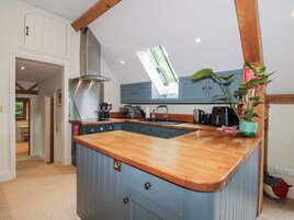 Una cocina con encimera de madera, extractor de acero inoxidable y ventana sobre el lavabo.