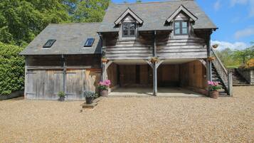 A wooden house with a gravel driveway, a covered porch, and a staircase leading to the entrance.