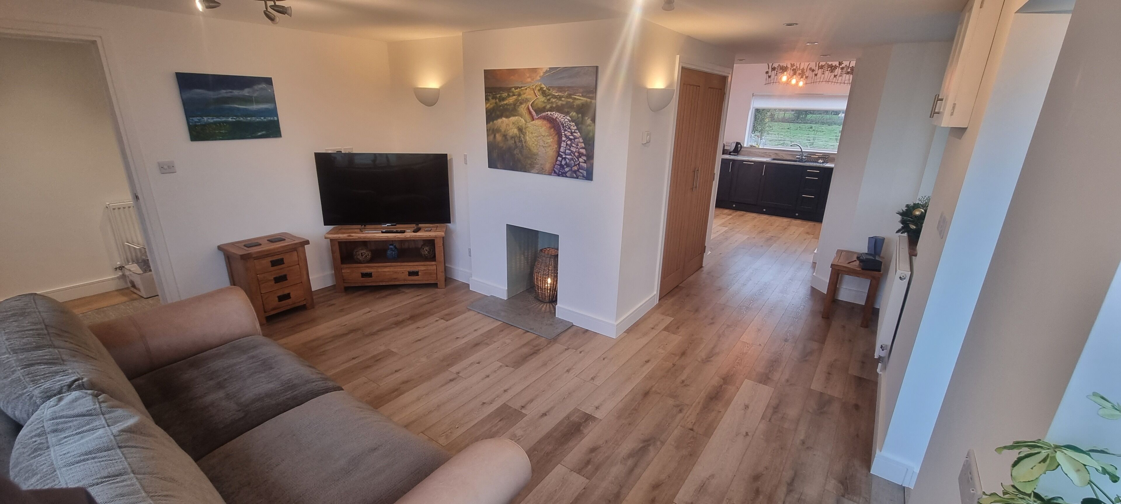 Una sala de estar con televisor de pantalla plana, mueble de madera para entretenimiento y chimenea.