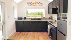 Una cocina moderna con armarios oscuros, un ventanal y vistas al exterior.