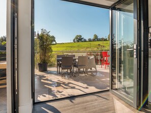 A modern glass door leading to an outdoor patio with wicker furniture and a view of a green field. - Step into indulgence, where every detail is tailored for your comfort. (Cradley, near Malvern)