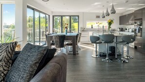 A modern kitchen with a dining area, large windows, and a view of greenery. - Step into indulgence, where every detail is tailored for your comfort. (Cradley, near Malvern)