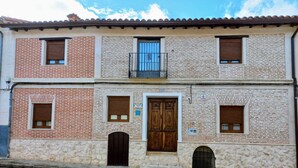 A two-story building with a stone facade, wooden doors, and windows with shutters.