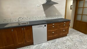 A kitchen with a dishwasher, wooden cabinets, a stainless steel sink, and a patterned backsplash.