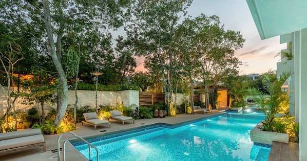 A swimming pool with lounge chairs and a well-maintained garden.