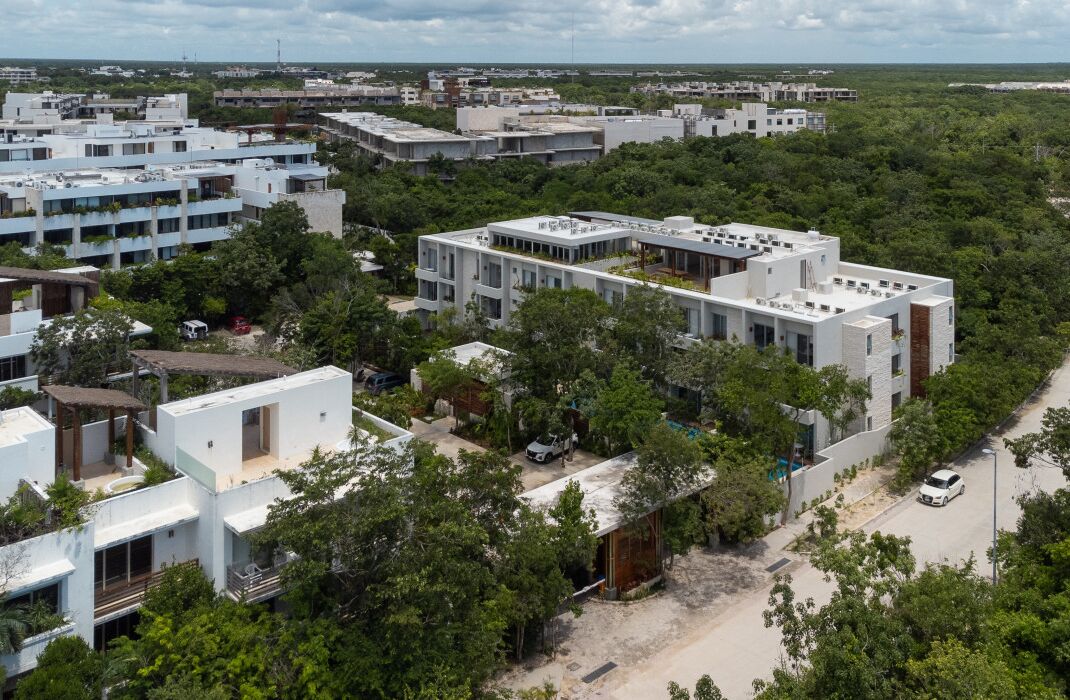 A modern residential area with multi-story buildings, surrounded by greenery and a clear sky.