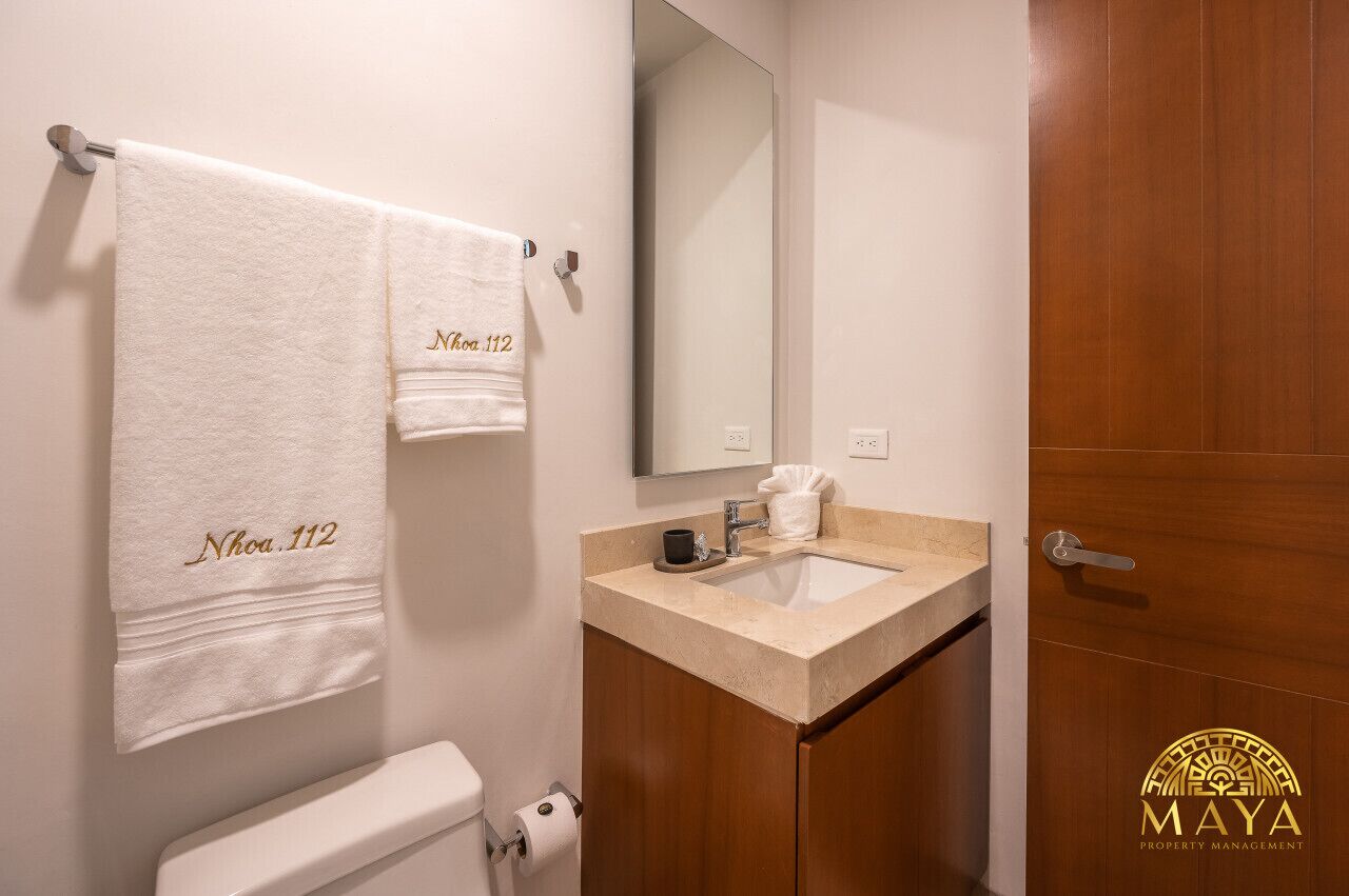 A bathroom with a toilet, sink, and a towel rack with towels.