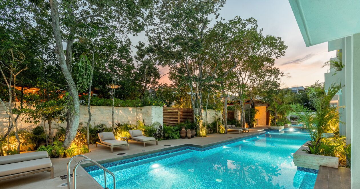 Une piscine dotée de chaises longues et d’un jardin bien entretenu.