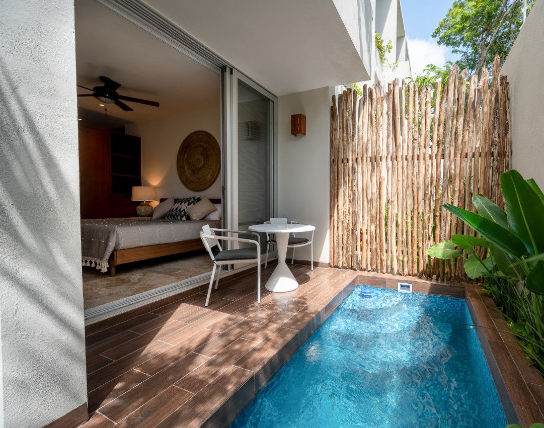 A small outdoor pool area with a wooden deck, a table, and chairs.