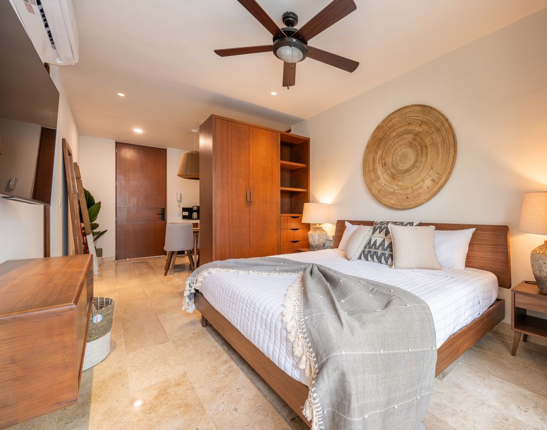 Camera da letto moderna con un letto grande, un armadio in legno, una ventola a soffitto e un decoro a forma circolare realizzato in fibre naturali.
