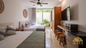 A modern hotel room with two beds, a ceiling fan, a TV, a kitchen area, and a sliding glass door to the outside.