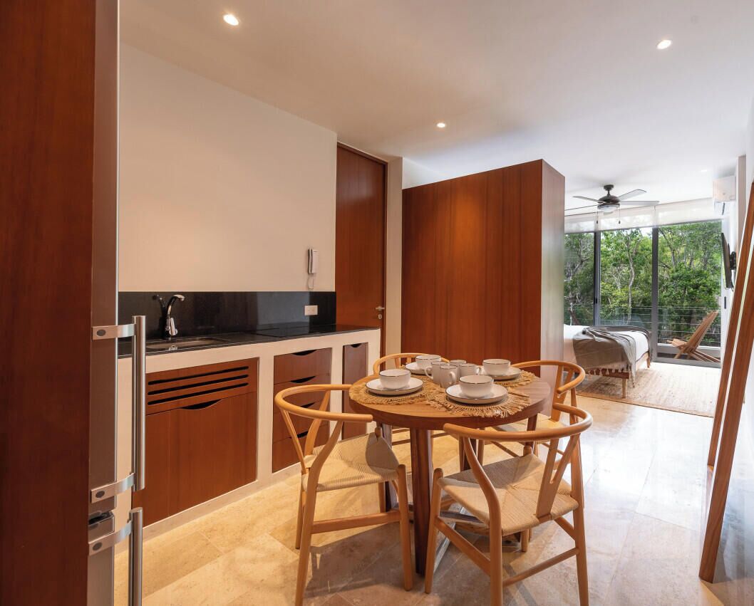 A modern kitchen with wooden cabinets, a dining table with chairs, and a view of the outdoors.