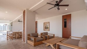 A spacious living area with a wooden sofa, a coffee table, and a dining table with chairs. - NHOA 208C Lux 1BR Condo Jungle View in Aldea Zama (Tulum)