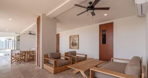 Ein modernes Wohnzimmer mit einer Holz-Sofagarnitur, einem Holztisch und einem Deckenventilator.