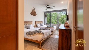 A bedroom with two beds, a ceiling fan, a large window, and a view of greenery outside. - NHOA 208C Lux 1BR Condo Jungle View in Aldea Zama (Tulum)