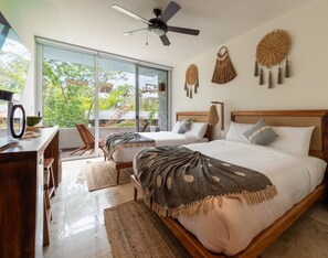 A bedroom with two beds, a ceiling fan, and large windows. - NHOA 207C Lux 1BR Condo Pool View in Aldea Zama (Tulum)