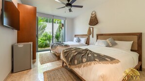 A bedroom with a bed, a ceiling fan, a TV, and a refrigerator. - NHOA 102A Lux 2BR Condo Plunge Pool in Aldea Zama (Tulum)