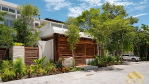 A modern building with a stone facade, wooden shutters, and lush greenery.