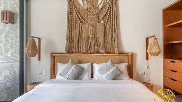 Una habitación de hotel con una cama grande, cabecera de madera y un colgador de macramé en la pared.