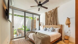 A bedroom with a bed, a ceiling fan, a large window, and a view of greenery outside.