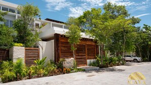 A modern building with a stone facade, wooden shutters, and lush greenery.