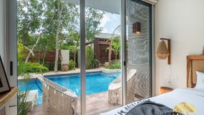 Et soveværelse med en stor skydedør, der fører til et privat poolområde.