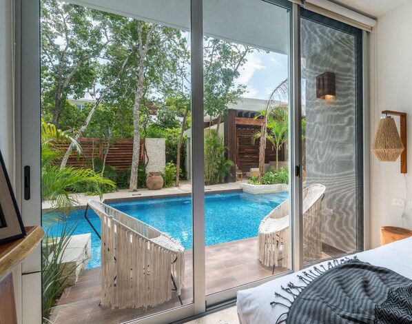 A bedroom with a large sliding glass door leading to a private pool area.
