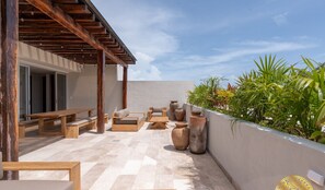 A rooftop terrace with wooden furniture, large planters, and a view of greenery. - NHOA 107A Lux 2BR Condo Pool access in Aldea Zama (Tulum)