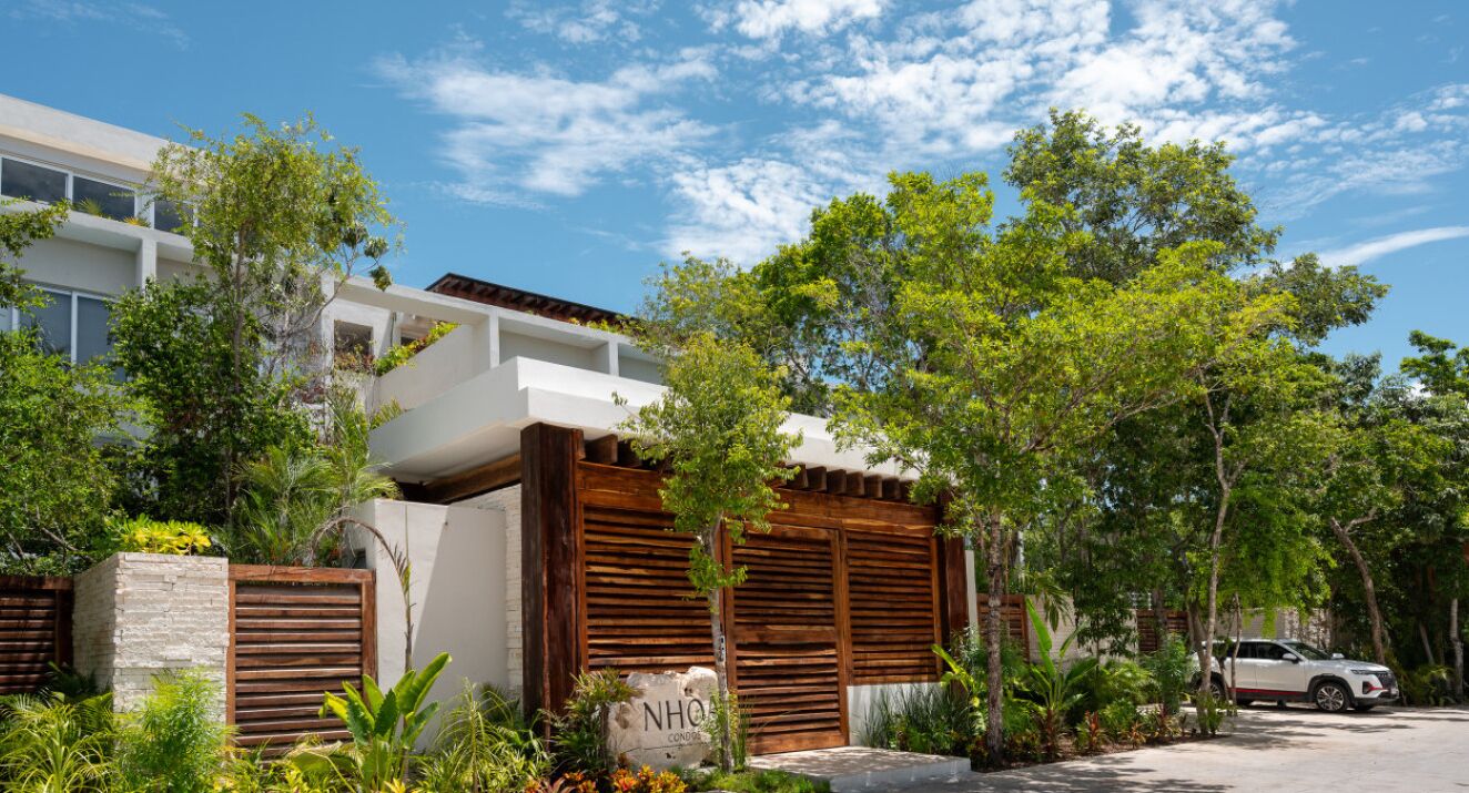 A modern house with a white exterior, wooden shutters, and a stone foundation.