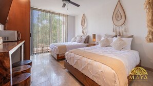A hotel room with two beds, a desk, and a ceiling fan.