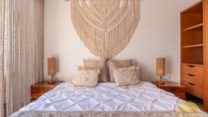 Een slaapkamer met een groot bed, twee nachtkastjes en een houten garderobe.