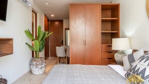A bedroom with a bed, a wardrobe, a desk, and a chair.