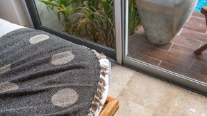 Une chambre avec vue sur une piscine, une table en bois et un tissu à motifs posé sur un présentoir.