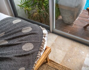 A room with a view of a swimming pool, a wooden table, and a patterned fabric on a stand. - NHOA 101A Lux 2BR Condo Pool access in Aldea Zama (Tulum)