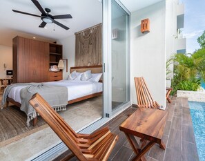 A modern bedroom with a bed, wooden furniture, a ceiling fan, and a glass door leading to a pool area. - NHOA 101A Lux 2BR Condo Pool access in Aldea Zama (Tulum)