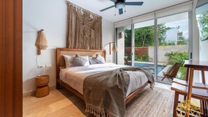 A bedroom with a bed, a ceiling fan, a large window, and a view of a swimming pool. - NHOA 101B Lux 1BR Condo Pool access in Aldea Zama (Tulum)