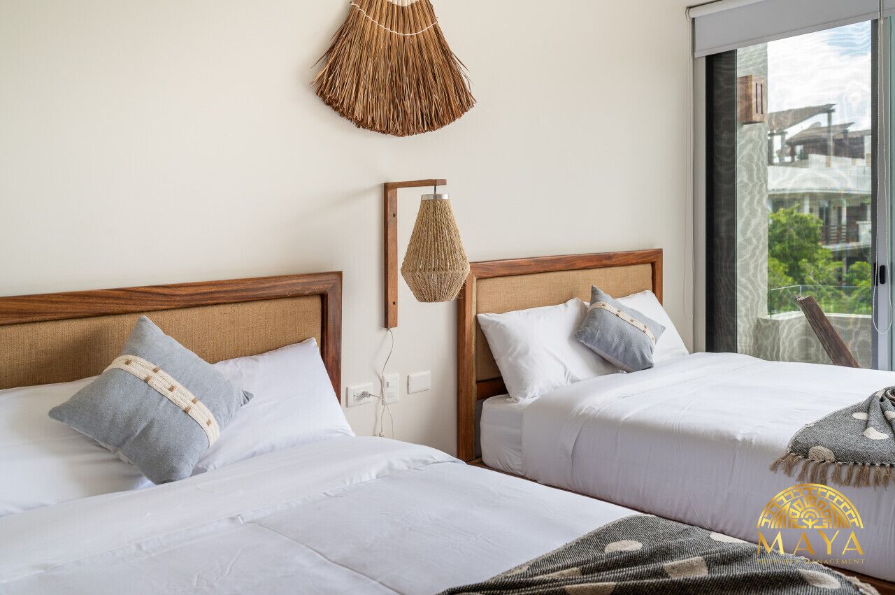 Une chambre d’hôtel avec deux lits, une grande fenêtre et une tapisserie murale tissée.
