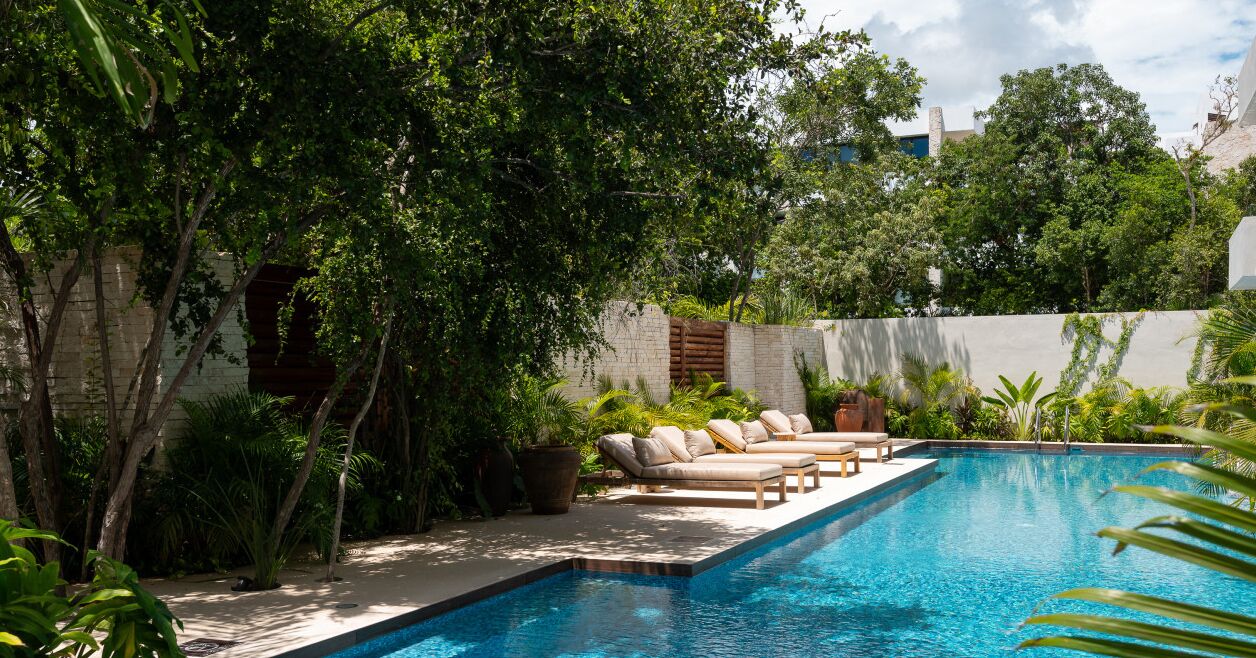 A swimming pool with lounge chairs and potted plants.