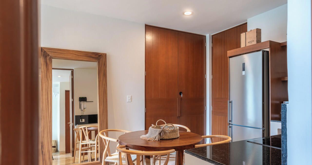 Une cuisine moderne avec des meubles en bois, un réfrigérateur en acier inoxydable et un coin repas comprenant une table ronde et des chaises.