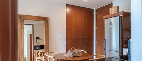 Une cuisine moderne avec des meubles en bois, un réfrigérateur en acier inoxydable et un coin repas comprenant une table ronde et des chaises.