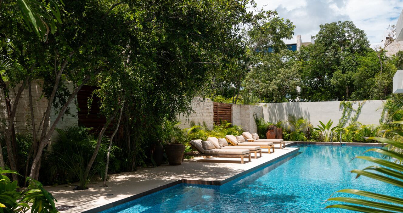 A swimming pool with lounge chairs and lush greenery.