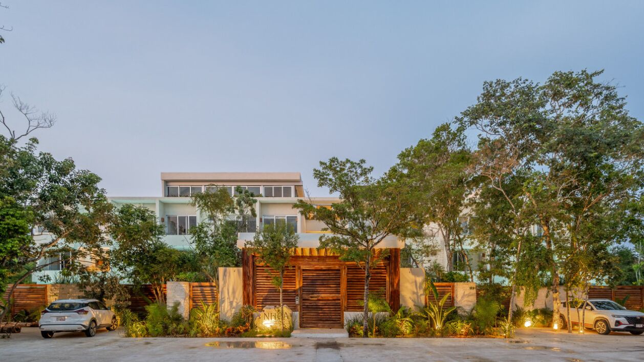 A modern two-story house with a large driveway and a gated entrance.