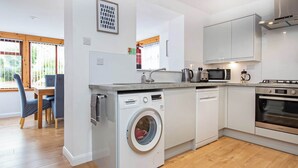 A modern kitchen with a Bosch washing machine, a microwave, a stove, and a dishwasher. - 2 bedroom accommodation in Nairn (Nairn)